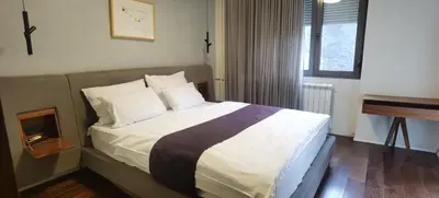 a bedroom with a bed with white sheets and a piano at Calm & Central Two Bedroom Apartment in Belgrade