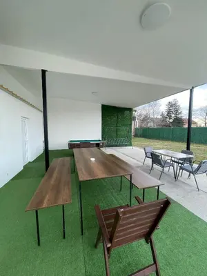 a group of tables and benches in a room with grass at Stan na dan Pecinci in Pećinci