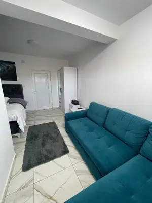 a blue couch in a living room with a bed at Stan na dan Pecinci in Pećinci