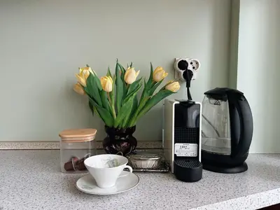 a counter with a vase of yellow tulips and a cup of coffee at Ollio - Art of Dorcol in Belgrade