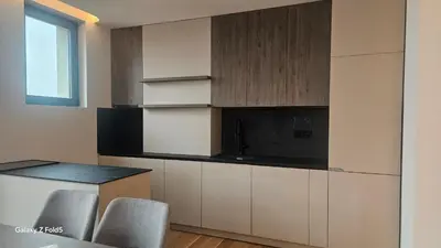 a kitchen with white cabinets and a counter with chairs at Zemun Golax Apartments in Belgrade