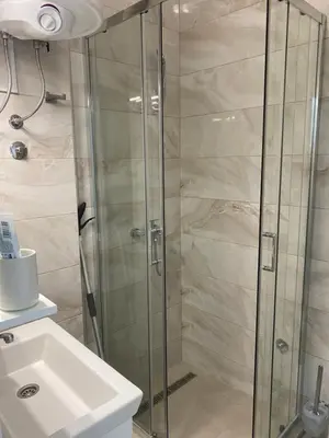 a shower with a glass door next to a sink at Apartman Titi in Smederevo