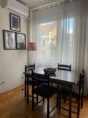 a dining room with a table and chairs and a window at Spacious apartment with 2 bedrooms in City Center, near Parliament and St Marks Church in Belgrade