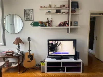 a living room with a flat screen tv and a guitar at Spacious apartment with 2 bedrooms in City Center, near Parliament and St Marks Church in Belgrade