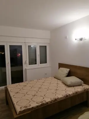 a bedroom with a large bed with two windows at Centro apartman 3 in Pančevo