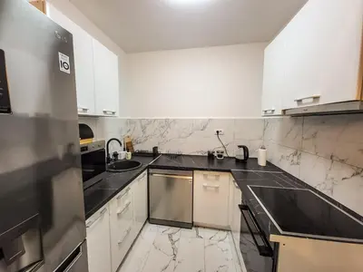 a kitchen with white cabinets and black counter tops at LOLA home in Beograd