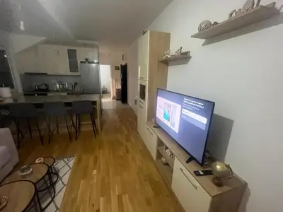 a living room with a flat screen tv and a kitchen at Harmony Apartment in Surčin
