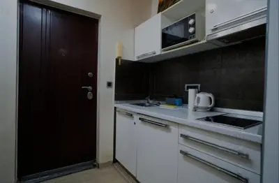 a kitchen with white cabinets and a black door at Moon in Belgrade