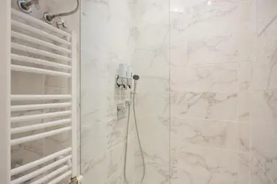 a bathroom with a shower with white marble tiles at Cozy City Center Nest - Quiet Courtyard Patio in Belgrade