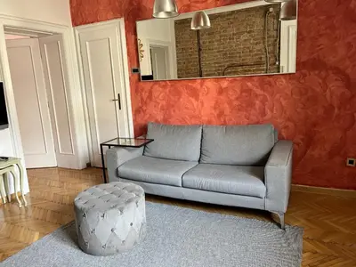 a living room with a couch and a stool at Centrala Apartment in Belgrade