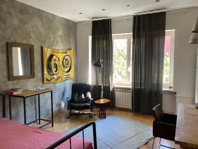 a bedroom with a bed and a chair and window at Centrala Apartment in Belgrade