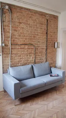a blue couch in front of a brick wall at Centrala Apartment in Belgrade