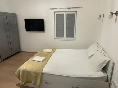 a bedroom with a bed with white sheets and a tv at Natalie's Lodge in Belgrade