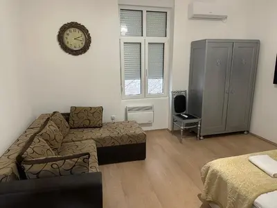 a living room with a couch and a clock on the wall at Natalie's Lodge in Belgrade