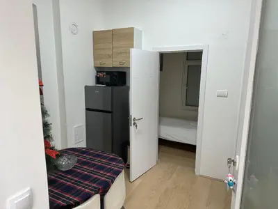 a small room with a refrigerator and a bedroom at Natalie's Lodge in Belgrade