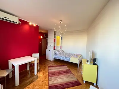 a room with a bed and a red wall at Bright modern downtown studio in Belgrade