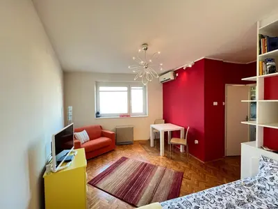 a living room with a red accent wall at Bright modern downtown studio in Belgrade