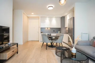 a living room with a table and chairs and a kitchen at Velora BW Metropolitan in Belgrade