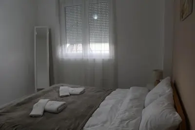 a bed with two towels on it with a window at Apartman Nina Banovci in Novi Banovci