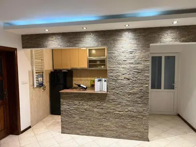 a kitchen with a stone wall and a counter at Elegance Apartman in Belgrade