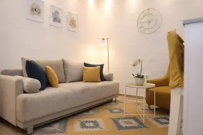 a living room with a couch and a table and a clock at VD City Centre Apartment Belgrade in Belgrade