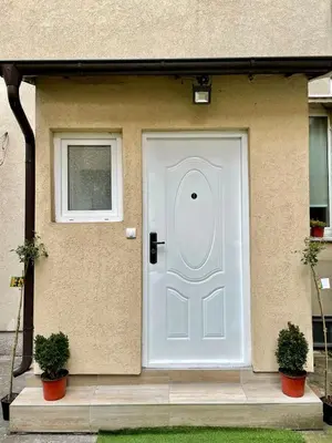 a white door on a house with two plants at VD City Centre Apartment Belgrade in Belgrade