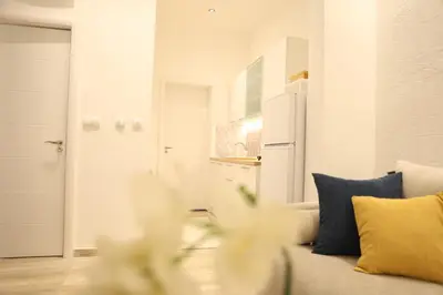a white living room with a couch and blue pillows at VD City Centre Apartment Belgrade in Belgrade