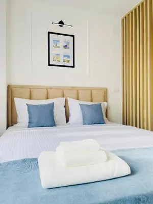 a white bed with blue pillows on top of it at Fontana Lux Apartment in Belgrade