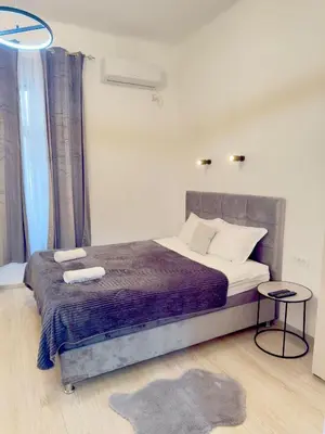a bedroom with a bed with a purple blanket and a table at Natalie's Prestige in Belgrade