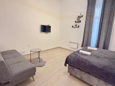 a bedroom with a bed and a couch and a tv at Natalie's Prestige in Belgrade