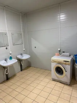 a laundry room with a washing machine and two sinks at Pecinci Hostel in Pećinci