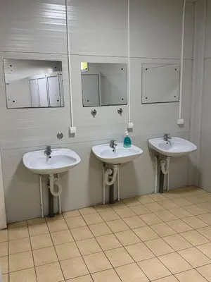 a bathroom with three sinks and mirrors on the wall at Pecinci Hostel in Pećinci