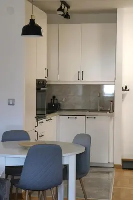 a kitchen with white cabinets and a table and chairs at Dok city apartman in Belgrade