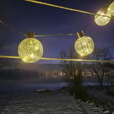 three lights hanging from a rope with a lake at night at Danube Retreat in Belgrade