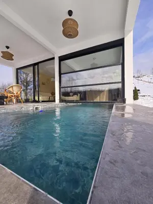 a swimming pool in a house with large windows at Lake & Pool Paradise in Karaula