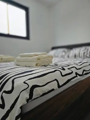 a bed with black and white sheets and a window at Lake & Pool Paradise in Karaula