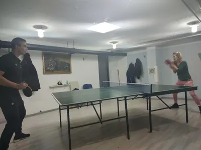 two people playing ping pong in a room with a ping pong table at River Sava apartman in Belgrade