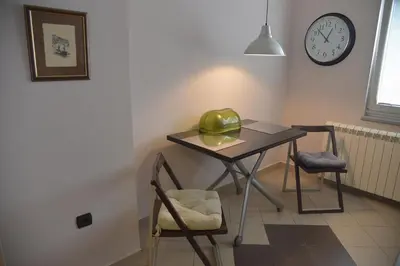 a table and two chairs in a room with a clock at Apartment Danica in Belgrade