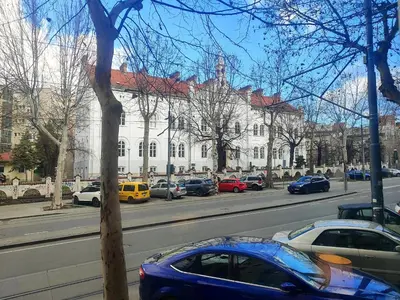 a blue car parked on a street in front of a building at Ollio Washington Apart in Belgrade