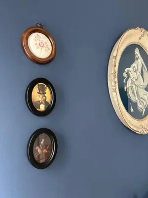 a blue wall with three framed pictures on it at Ollio Washington Apart in Belgrade