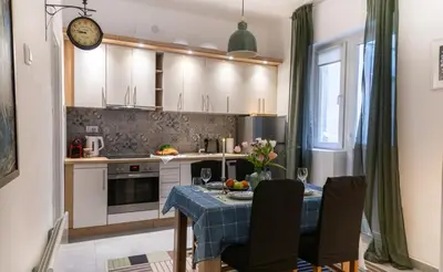 a kitchen with a table and chairs and a clock at Ollio Washington Apart in Belgrade