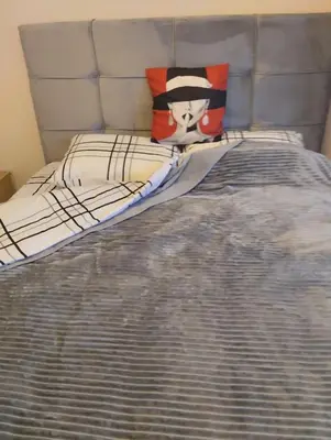 a bed with a comforter and a pillow on it at Apartman Lola in Lazarevac