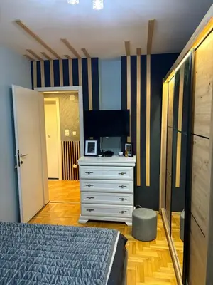 a bedroom with a bed and a dresser with a television at Apartman 23 in Belgrade