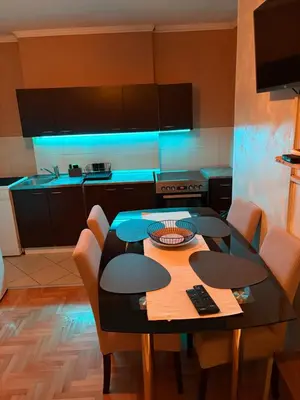 a kitchen with a table with chairs and blue lights at Apartman 23 in Belgrade