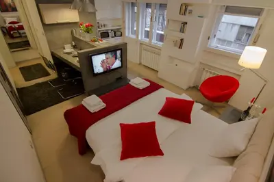 a bedroom with a large white bed with red pillows at Studio Apartment Picasso in Belgrade