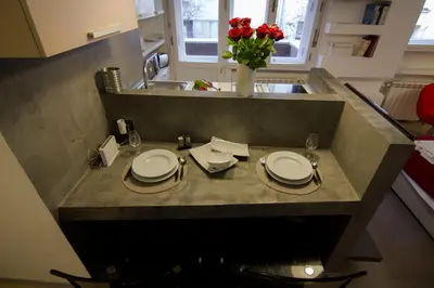a kitchen with a table with plates and a vase with roses at Studio Apartment Picasso in Belgrade