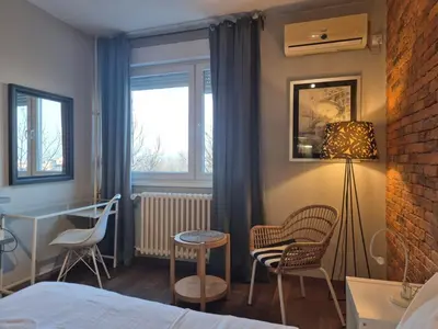 a bedroom with a bed and two chairs and a table at Apartment Madera in Belgrade