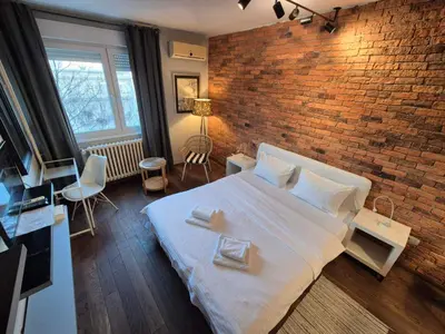 a bedroom with a white bed and a brick wall at Apartment Madera in Belgrade