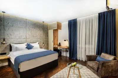 a bedroom with a king sized bed and a chair at One Luxury Suites in Belgrade