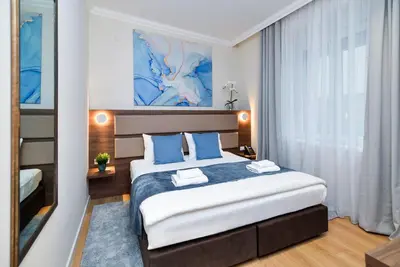 a hotel room with a large bed with blue pillows at Hotel Opera Garni in Belgrade